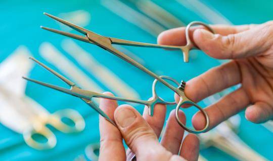 Hands holding two pairs of forceps and comparing them